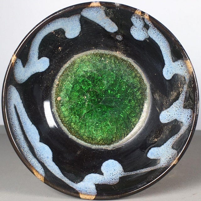 A striking Chinese ceramic tea bowl. The exterior features a deep, dark brown "tortoiseshell" glaze with a prominent, all-...