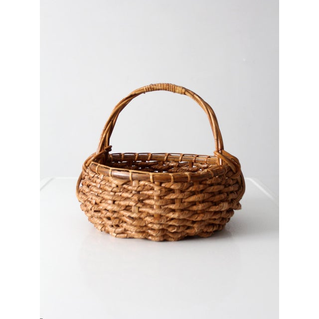 A vintage coil basket with a softly rounded form and an arched handle, finished in a warm natural tone. Easy and...