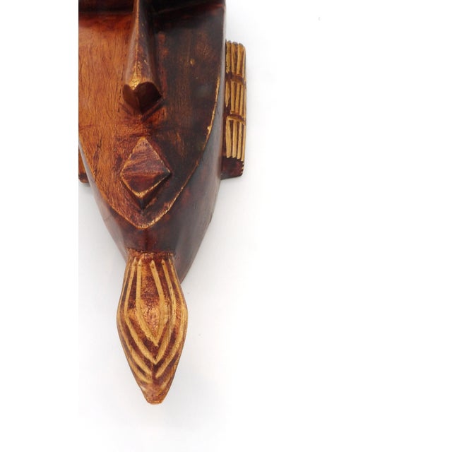 This hand-carved African wooden mask features a male face with stylized ears and a beard/goatee. It is a lovely addition...