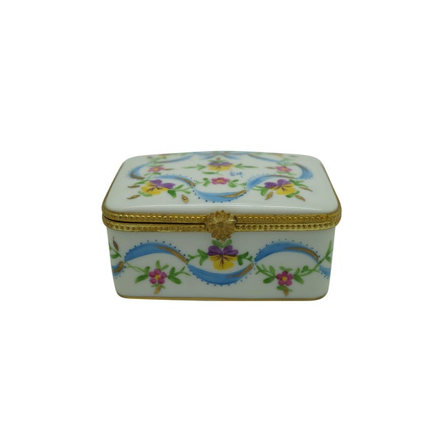 Vintage French Limoges hand-painted porcelain hinged trinket box featuring colorful floral motifs, blue ribbon swags, and...