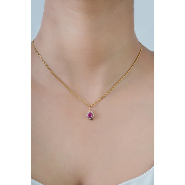 This elegant pendant features a vibrant 0.37 ct natural round ruby, set in 14K yellow gold. The center stone measuring 5.3...
