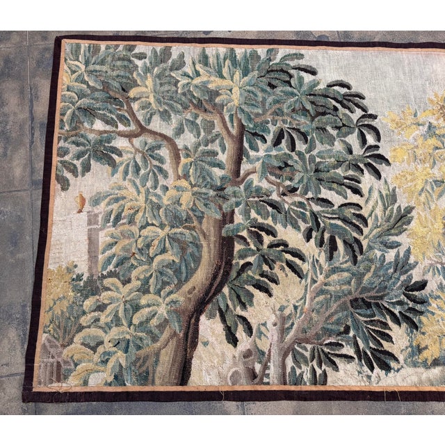 An authentic 17th century Flemish verdure tapestry depicting a tranquil woodland scene with mature trees and layered...