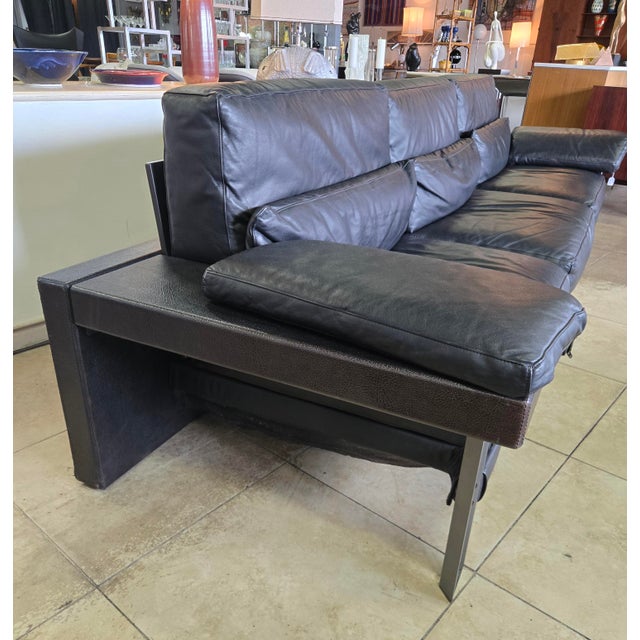 This low-profile three-seater is highly distinctive due to its thick, comfortable black leather cushions, wide track...