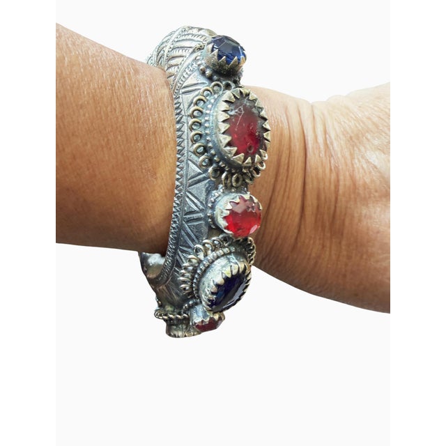 Vintage East Afghan tribal bangle bracelet featuring intricate high-relief geometric engravings and vibrant round and oval...