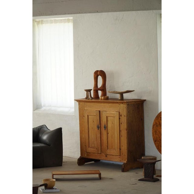 A charming Danish antique cabinet crafted in solid pine, dating to the mid to late 18th century. The piece features a warm...