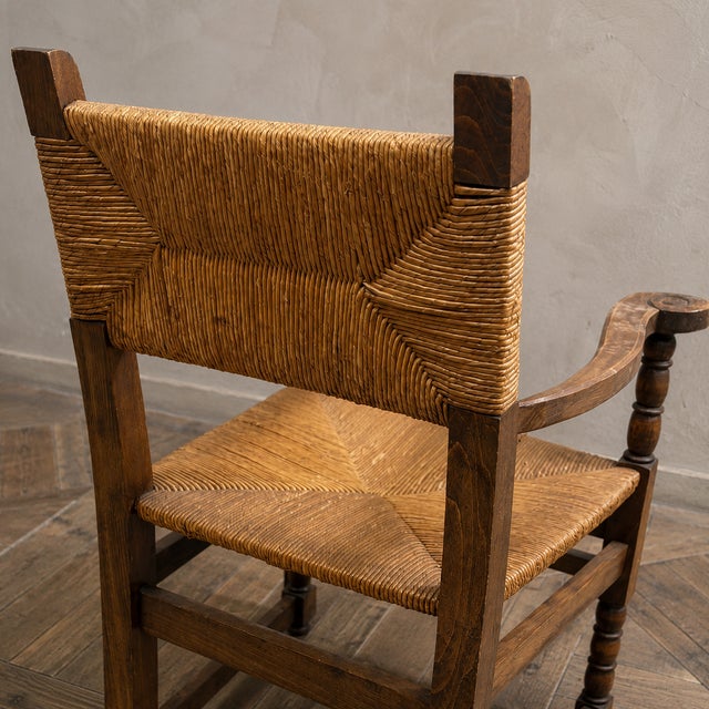 A vintage wicker armchair from the 1960s–1970s, featuring a handwoven seat and backrest with an elegant high-back...