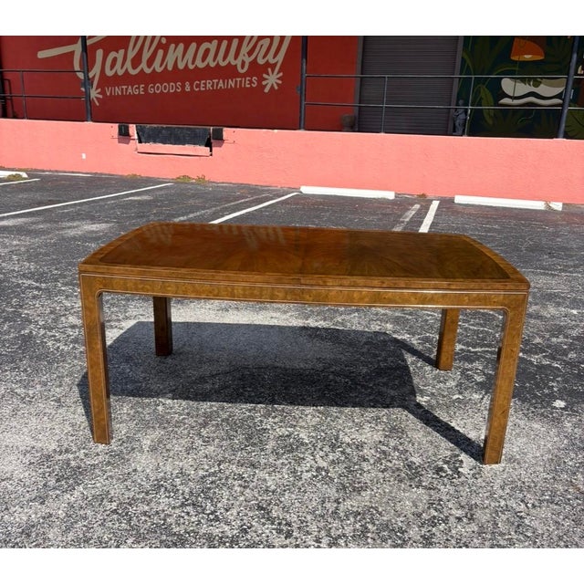 An exquisite Mastercraft dining table with striking burl accented throughout the table and gold trim along the border....