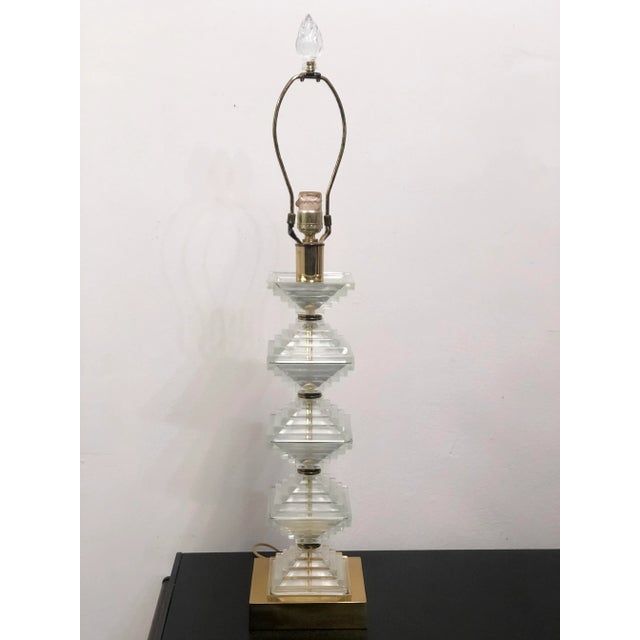 Mid-century Hollywood Regency style table lamp made of stacked cut glass in a graduating square pyramid shape atop brass...