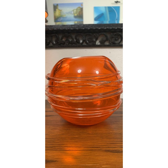 Striking vintage art glass bowl in a vivid translucent orange hue, featuring a sculptural rounded form with elegant ribbed...