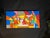 A large colorful geometric abstract canvas artwork featuring a bold cubist-style group scene with strong black linework...