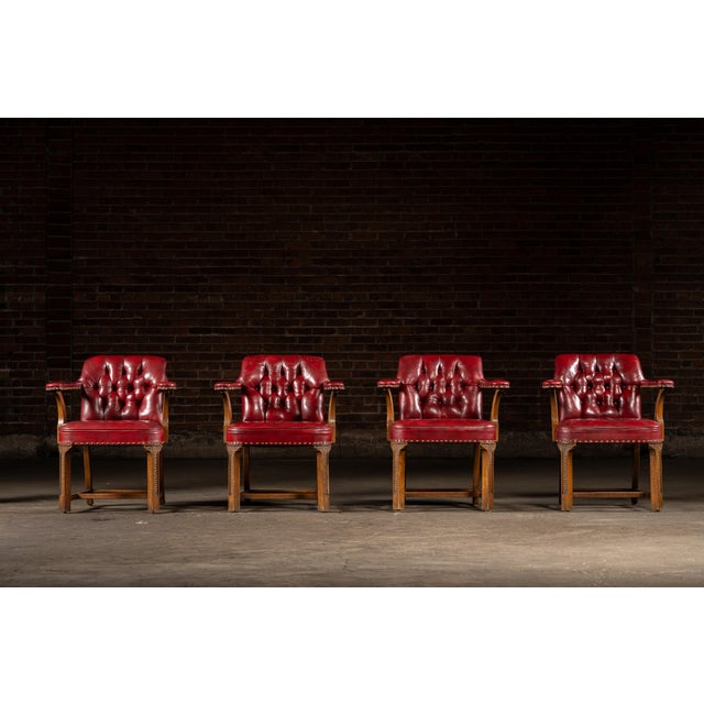 Set of four classic mid-century bankers chairs upholstered in deep oxblood red leather with button-tufted backs and brass...