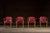 Set of four classic mid-century bankers chairs upholstered in deep oxblood red leather with button-tufted backs and brass...