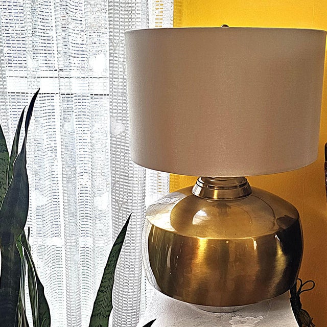 Vintage 1970s Ethan Allen table lamp featuring a sculptural orb-shaped body in brushed antiqued brass paired with a wide...