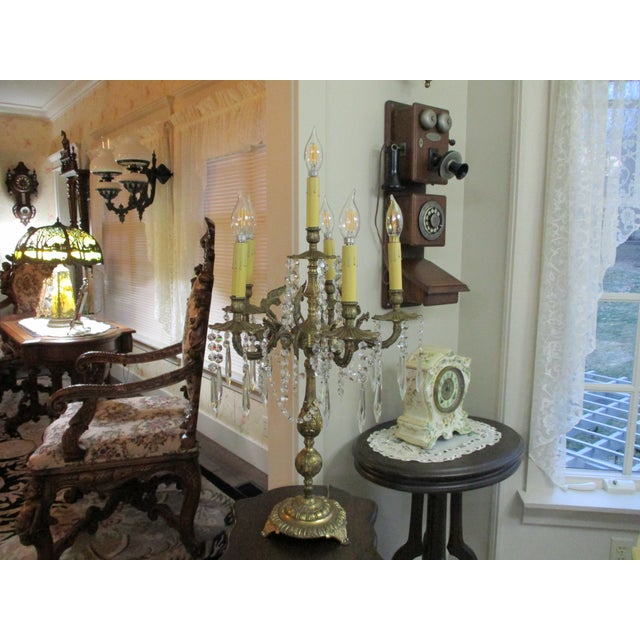 The product is a large antique brass candelabra lamp with six light bulbs, art nouveau crystal prisms with angel wings....