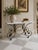This mid-century Reproduction French Patisserie table, crafted from steel and brass, boasts a rectangular white marble top...