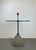 Sculptural Post-Modern side table featuring a textured concrete base, a black enameled steel central column, and a round...