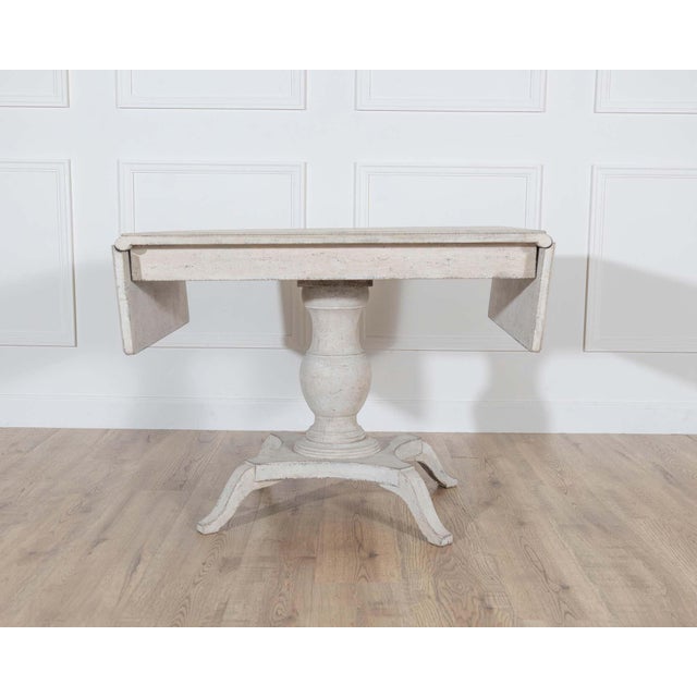 A charming Swedish table from around 1880, designed with two drop-leaf flaps that allow the piece to expand or contract as...