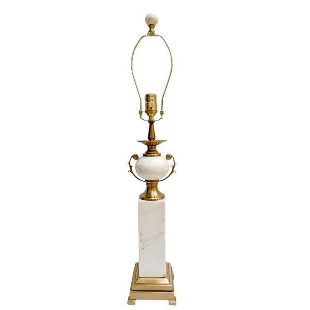 An elegant pair of Neoclassical style table lamps, featuring a polished brass plated and veined cream marble construction....
