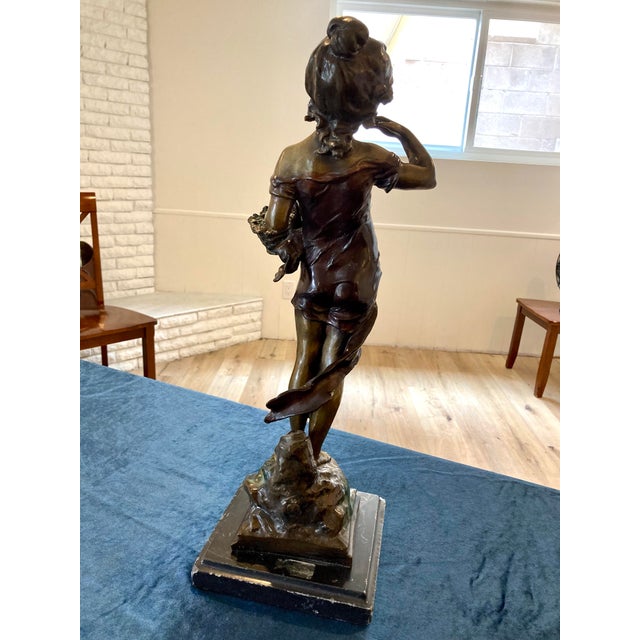 Charming antique French bronze sculpture by A. Moreau, depicting a young girl in flowing dress holding a woven basket,...