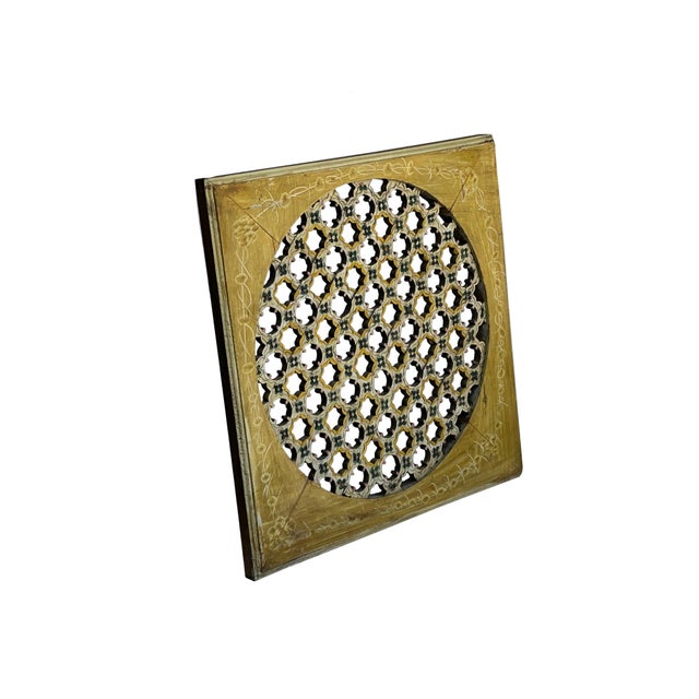 This handcrafted wooden architectural panel features a circular jali (fretwork) screen set within a square, mustard-yellow...