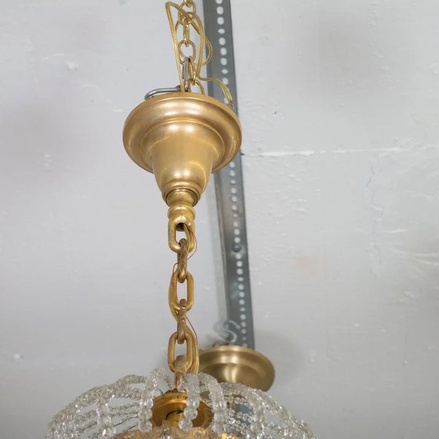 Gilt metal finish Montgolfier style chandelier featuring various styles of crystal drop elements and cast flower bobeches....