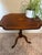 An elegant antique tilt-top table, finely crafted with rich wood grain, graceful proportions, and a striking shell-form...