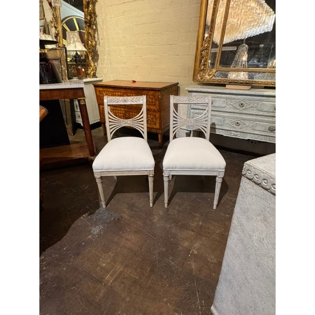 The product is a pair of early 20th century Swedish painted side chairs. These chairs have a classic, timeless style,...