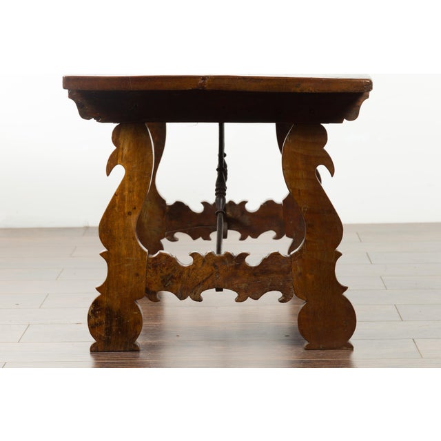 An Italian low fratino walnut table from the early 19th century, with wrought iron stretchers. Created in Italy during the...