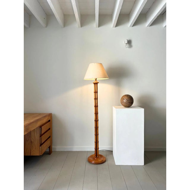 A 20th century floor lamp of faux bamboo form. This striking standing lamp has a structure of three turned wooden stems...