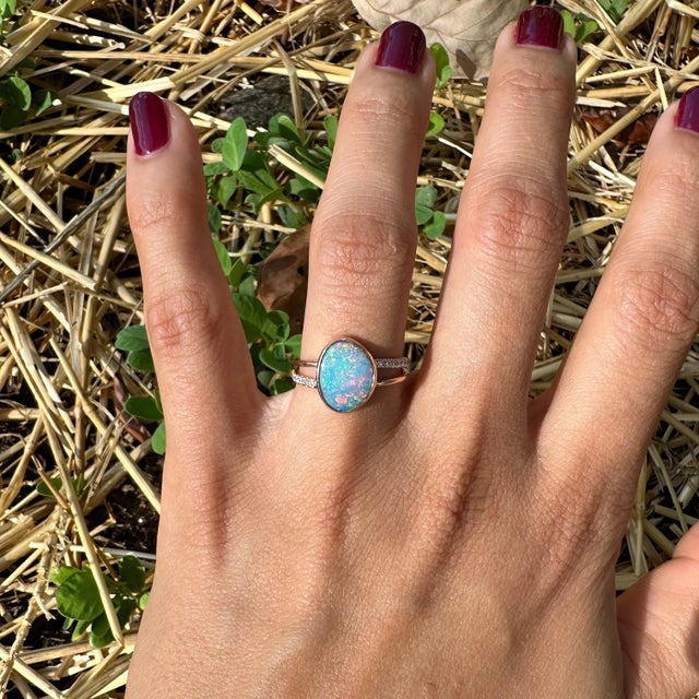 This striking cocktail ring showcases a captivating 1.83 carat Boulder Opal in a cabochon cut, complemented by round...