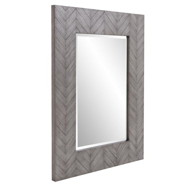 The Cavalier Mirror features a rectangular wood frame detailed with a chevron pattern. It is finished in a gray wash that...