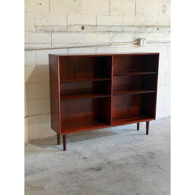 This elegant open shelving unit features a clean double-column layout with a mid-height frame. The minimalist cabinet...