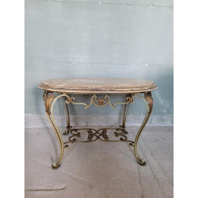 Antique hand-forged wrought iron coffee table with marble top, enclosed by a wooden frame that follows the entire line of...