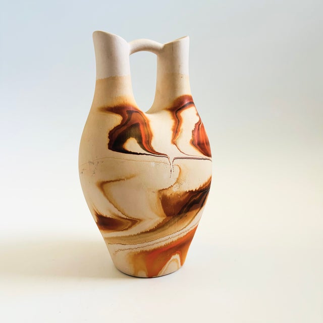 A large vintage Nemadji Pottery wedding vase with a dramatic organic pattern of orange and brown swirls on a light off-...