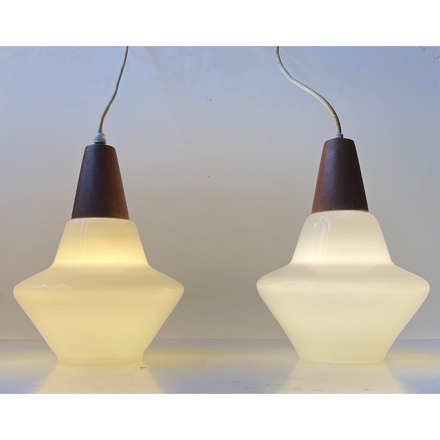 A pair of hand-blown cased white opaline glass pendant lights manufactured by Holmegaard in Denmark during the late 1960s....