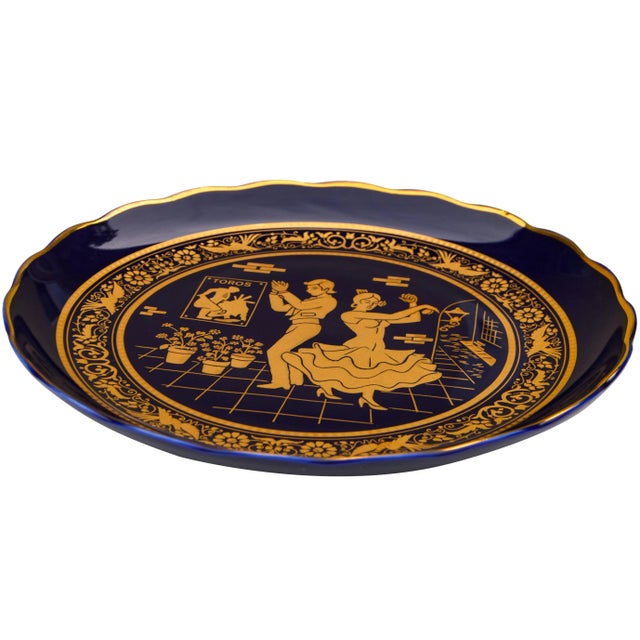 Vintage dark blue and gold porcelain plate featuring ornate hand-painted scenes with intricate floral pattern and...