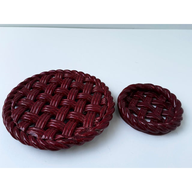 Charming pair of mid-century Vallauris, France ceramic trivets in a rich burgundy/oxblood glaze, featuring an intricate...