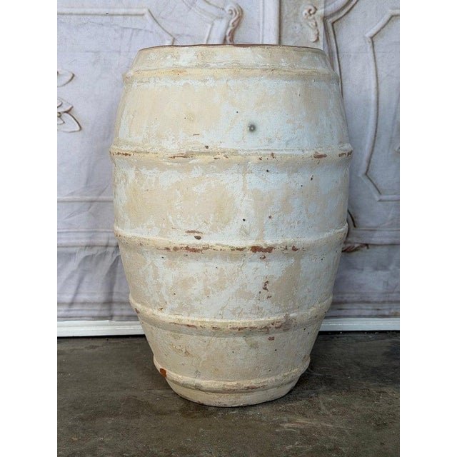 A striking terracotta storage vessel featuring a bold, sculptural silhouette defined by its horizontal ribbed bands and...