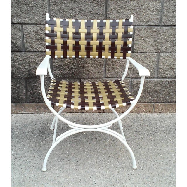 A single Campaign style patio chairs in white powder coated aluminum with brown and gold heavy duty vinyl upholstery in a...