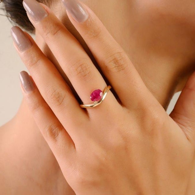 This elegant wave solitaire ring in 14K white gold showcases a 1.14 carat oval cut natural ruby, measuring approximately...