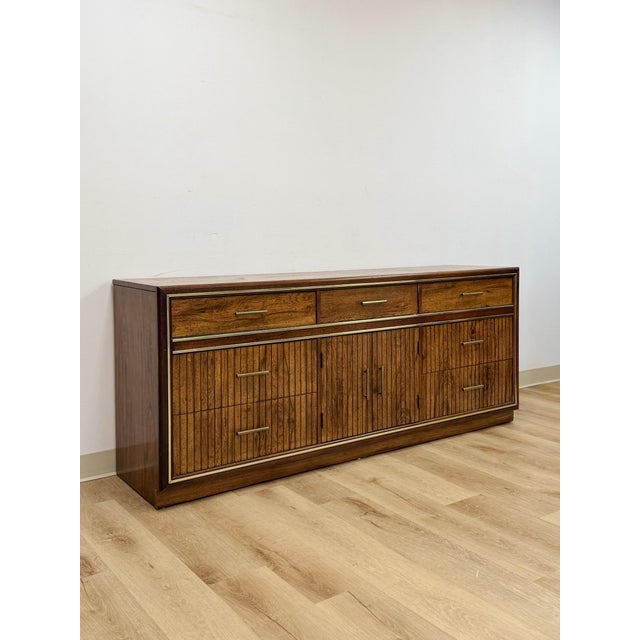 This vintage nine-drawer dresser by Bassett showcases a distinctive mid-century postmodern silhouette, combining rich wood...