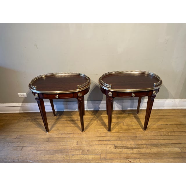 This elegant pair of Regency-style side tables features one central drawer and two pull-out side drawers, offering both...