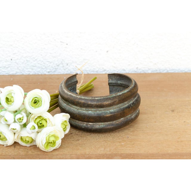 This bronze exchange is a storied artifact of West African economic history. Known as a Manilla, these open-cuff bracelets...