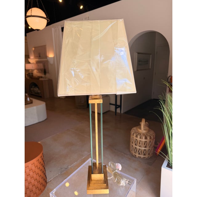 This contemporary transitional table lamp showcases a refined mix of gilded iron and tempered glass, creating a...