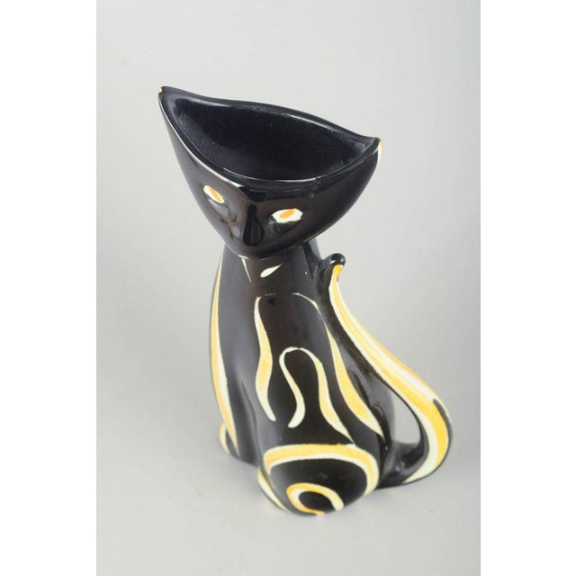 West Germany Ceramic vase, 1970s. Elegant and stylised ceramic vase shaped as a cat, in black glaze with hand-painted...