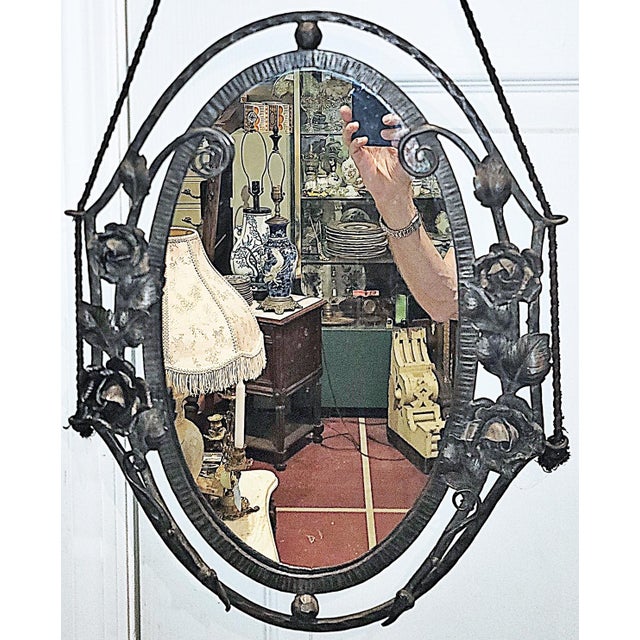 A metalworkers dream, this 1920s cast and wrought steel oval hanging wall mirror, hand chased double metal frame adorned...