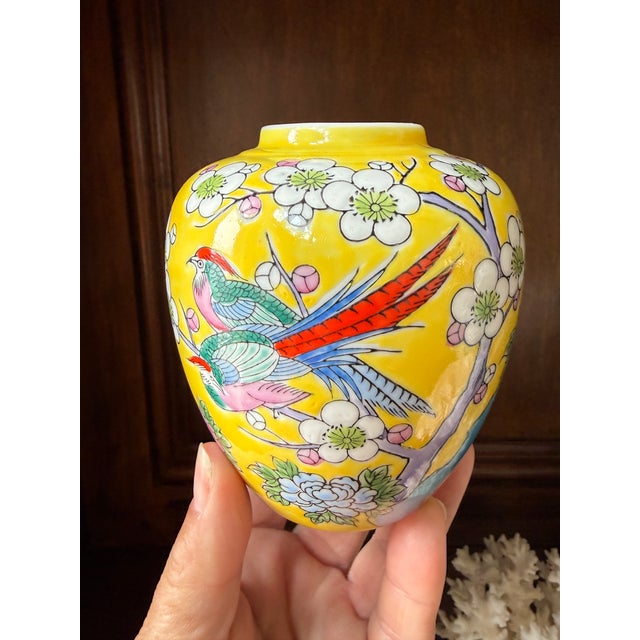 This vibrant vintage chinoiserie-style ginger jar features colorful pheasants perched among blooming branches against a...