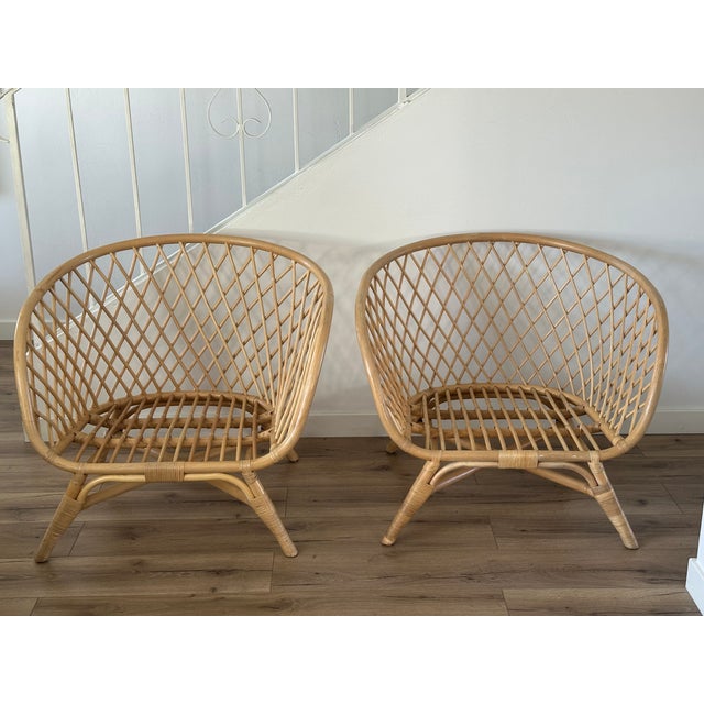 A stylish pair of vintage rattan lounge chairs featuring a sculptural low-profile silhouette and beautifully woven lattice...