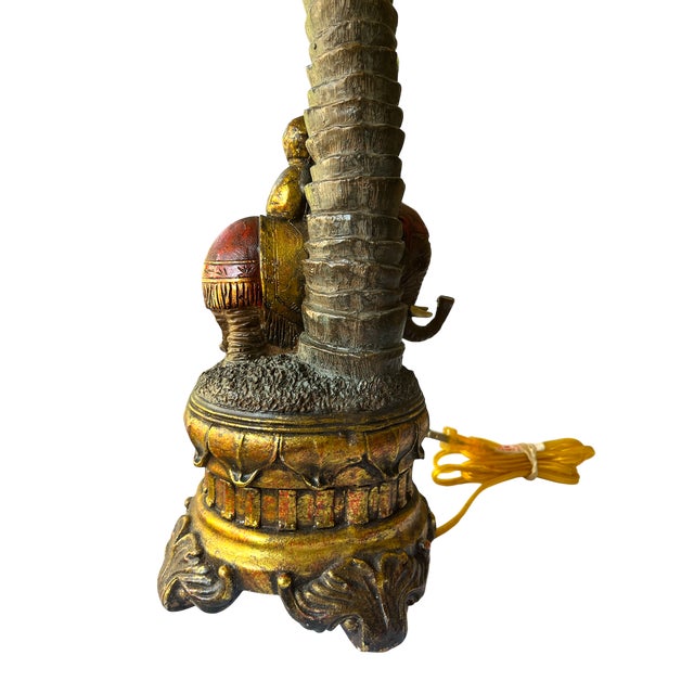 1990s tropical revival table lamp, featuring a richly detailed base with an elephant and rider under a towering palm tree....