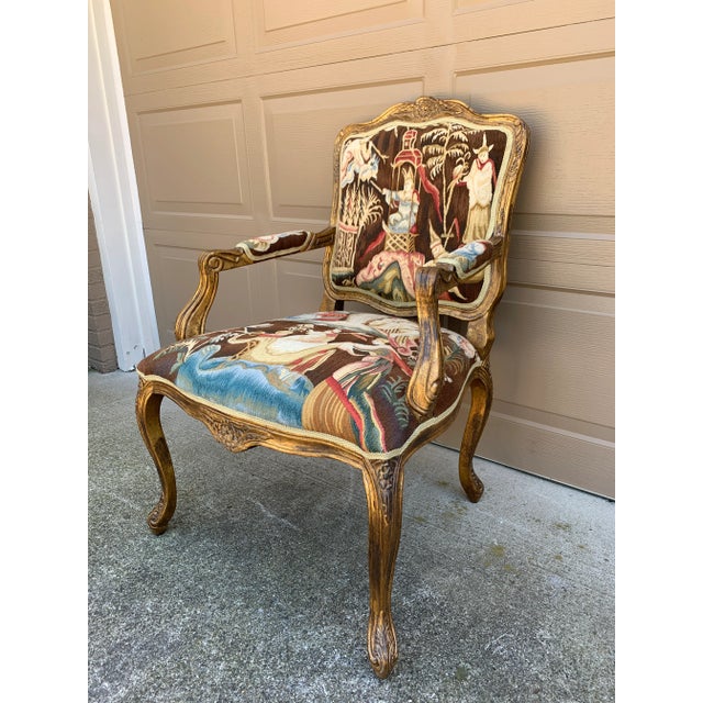 An elegant French Provincial Louis XV style fauteuil showcasing a beautifully carved giltwood frame upholstered in richly...